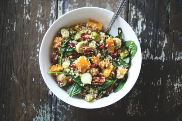 Winterlicher Rosenkohl-Salat mit Granatapfelkernen, Feta und gerösteten Mandelsplittern, serviert in einer Schüssel