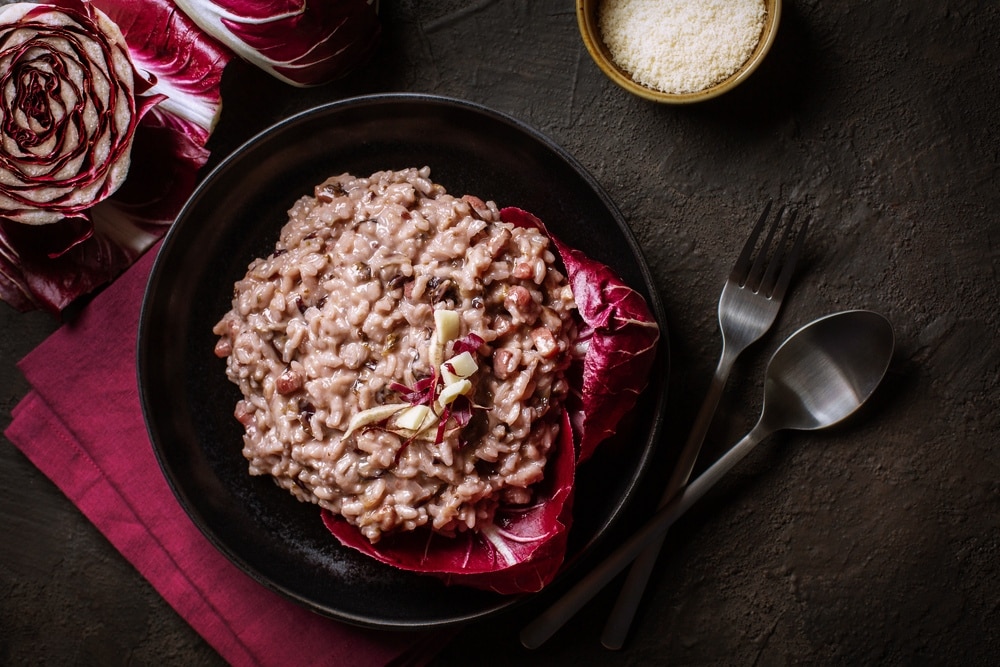 Radicchio-Risotto mit Walnüssen und fluffigem Orangenschaum, angerichtet auf einem weißen Teller