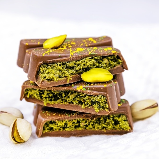 Nahaufnahme von luxuriöser Dubai-Schokolade mit Zartbitterschokolade, einer Pistazienfüllung und knusprigem Engelshaar. Dekoriert mit gehackten Pistazien und essbaren Goldflocken.