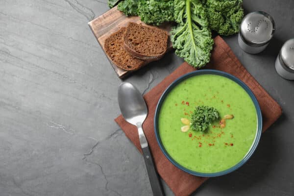 Vegetarische Grünkohlsuppe in einer Schale, dekoriert mit karamellisierten Zwiebeln und Chiliflocken.