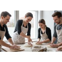 Teilnehmer eines Sauerteigkurses sitzen an einem Holztisch und verkosten verschiedene frisch gebackene Brotvariationen.