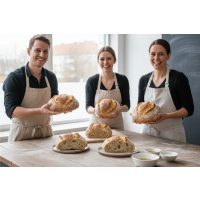 Drei stolze Bäcker präsentieren ihre selbstgebackenen Sauerteigbrote nach einem erfolgreichen Backkurs.