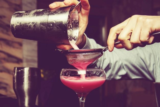 Cocktailkurs-Gutschein – Mann siebt pinken Cocktail