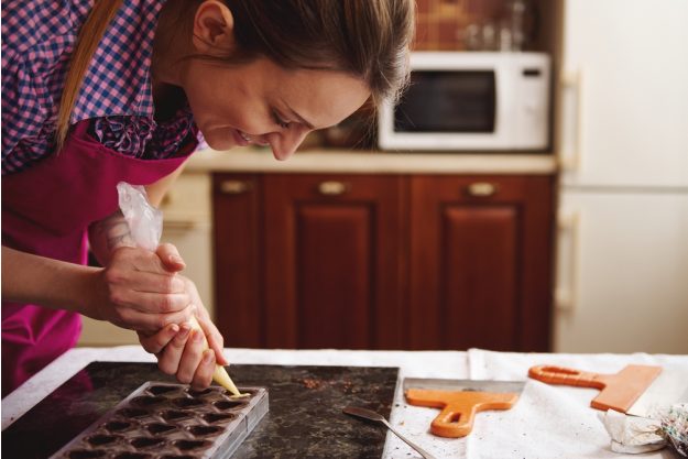 Pralinenkurs Augsburg – Frau füllt Schokolade in Pralinenform