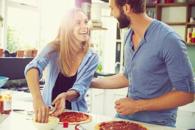 Single-Kochkurs Bonn– Frau und Mann lachen und belegen gemeinsam eine Pizza